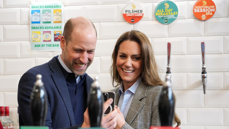 Prince William and Princess Kate smiling and taking a selfie.