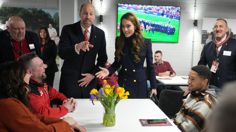 Kate Middleton and Prince William in long blue coats at a football stadium