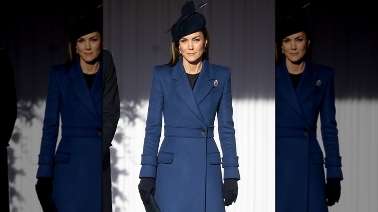 Kate Middleton smiling and wearing a long blue coat