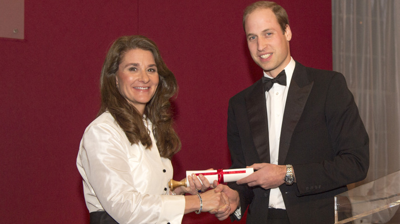 Melinda Gates and Prince William shaking hands and smiling in formal attire