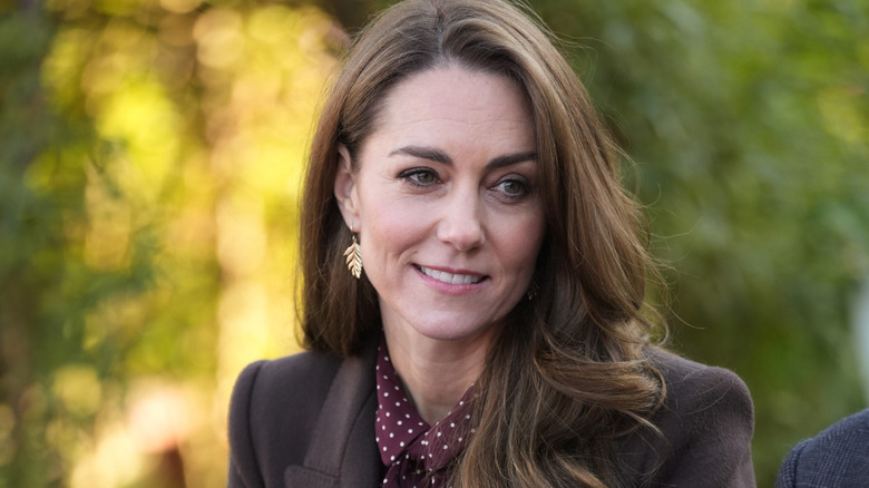 A smiling Princess Catherine in a brown coat and polka-dot blouse