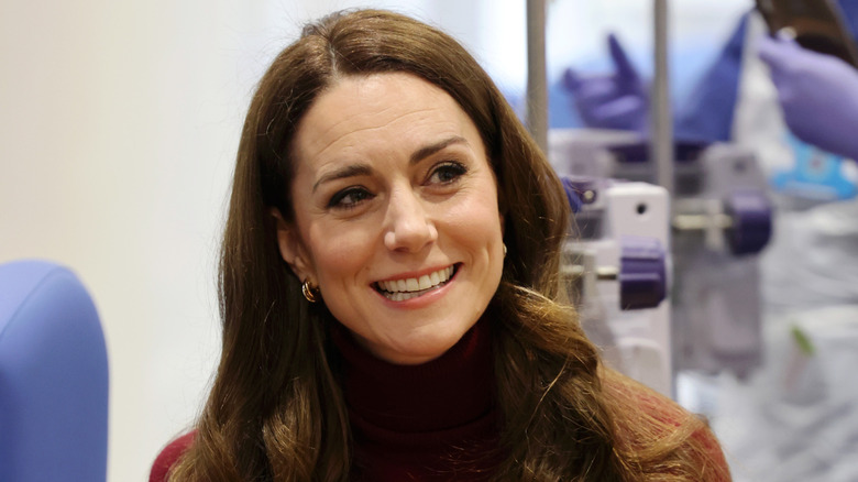 Kate Middleton smiles in a red sweater.