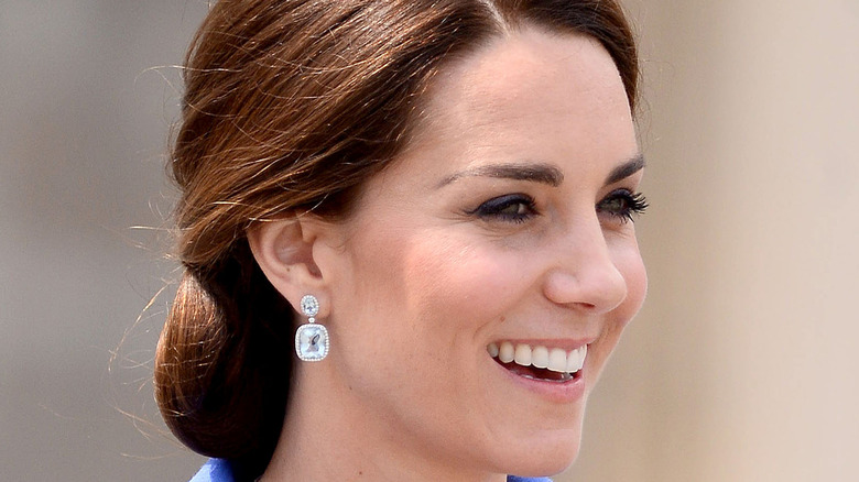 Kate Middleton smiling looking into the distance with diamond earring