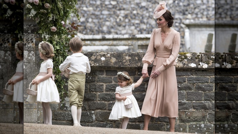 Princess Catherine holding Princess Charlotte's hand.