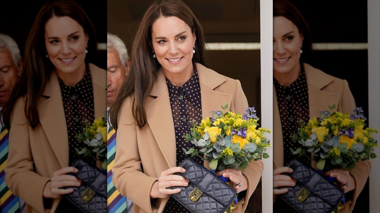 Princess Catherine in navy and yellow polka dot dress with tan coat holding flowers and purse