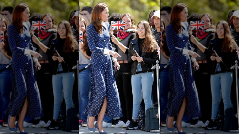 Princess Catherine greeting onlookers in a navy and white dress with high slit