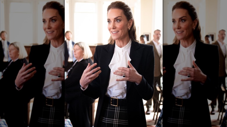 Kate Middleton speaking while wearing a white top and blazer