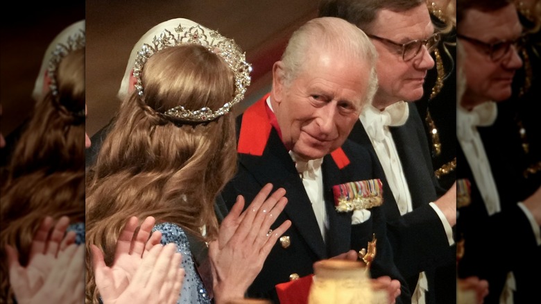 King Charles III smiling at Kate Middleton, who is wearing a tiara and sparkly nails