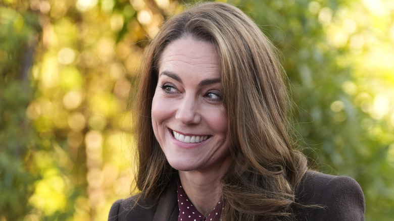 Kate Middleton smiling in a brown pantsuit