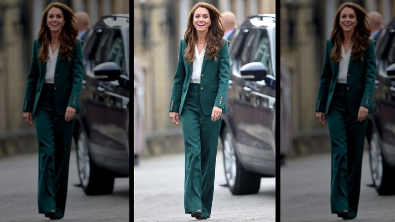Kate Middleton smiling in a green pantsuit and white blouse while walking outside in Leeds