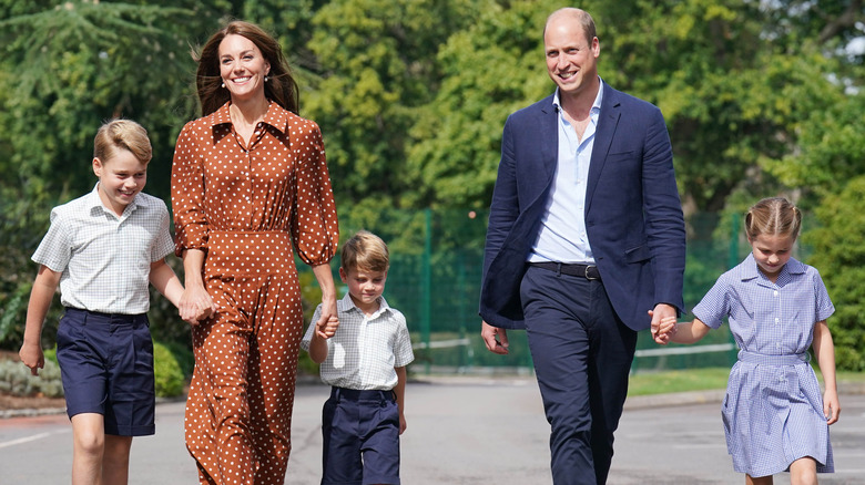 Kate Middleton and Prince William smiling and walking with their kids