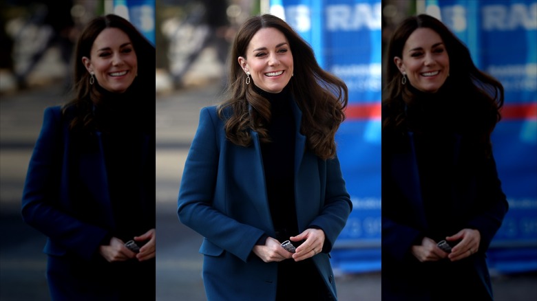 Kate Middleton smiling, hair blowing in the breeze.