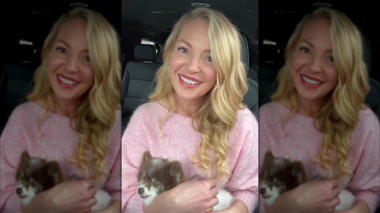 Katherine Heigl smiling and cuddling a dog in a pink sweater