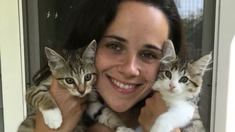 Carrie Monahan smiles while holding two kittens