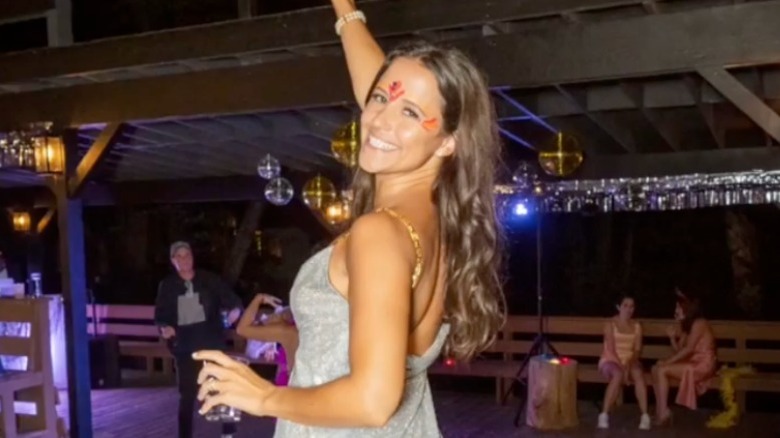 An adult Ellie Monahan with face paint looking behind her and smiling