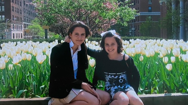 Ellie and Carrie Monahan posing in front of flowers