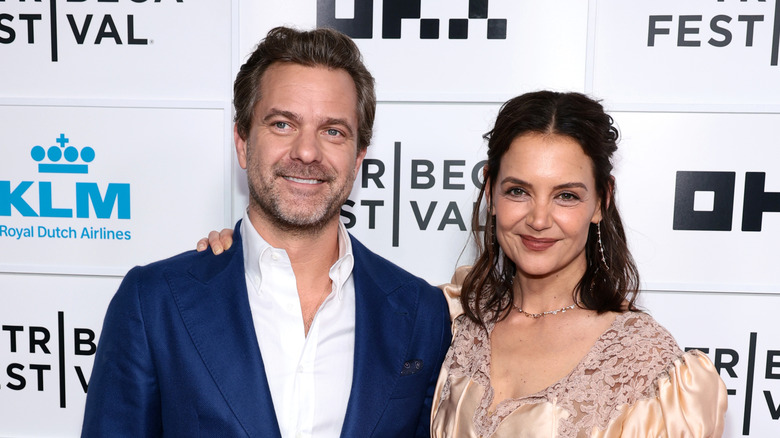 Katie Holmes and Joshua Jackson stand arm-in-arm and smile at a red carpet event