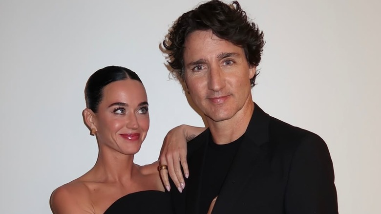 Katy Perry and Justin Trudeau posing together in front of a white wall