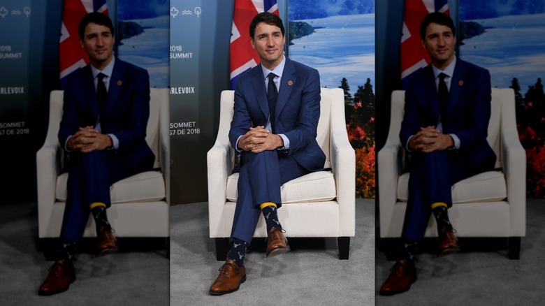 Justin Trudeau sitting down at the G7 Summit in 2018 wearing a suit and novelty socks