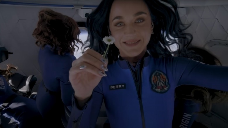Katy Perry holding up a daisy while on a Blue Origin flight
