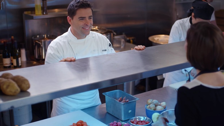 Kavan Smith smiling behind the kitchen counter in "Love On The Menu"