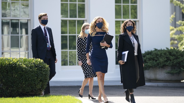 Kayleigh McEnany wearing a dark blue dress and mask.
