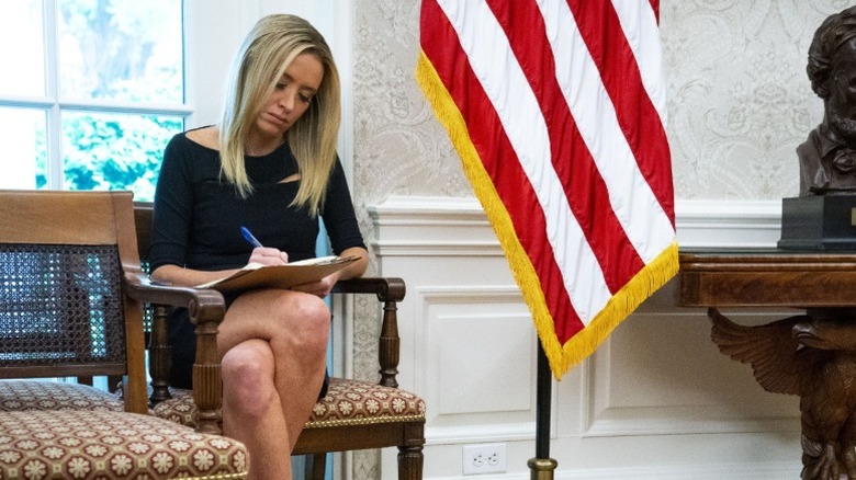 Kayleigh McEnany writing notes on a notepad with her legs crossed.