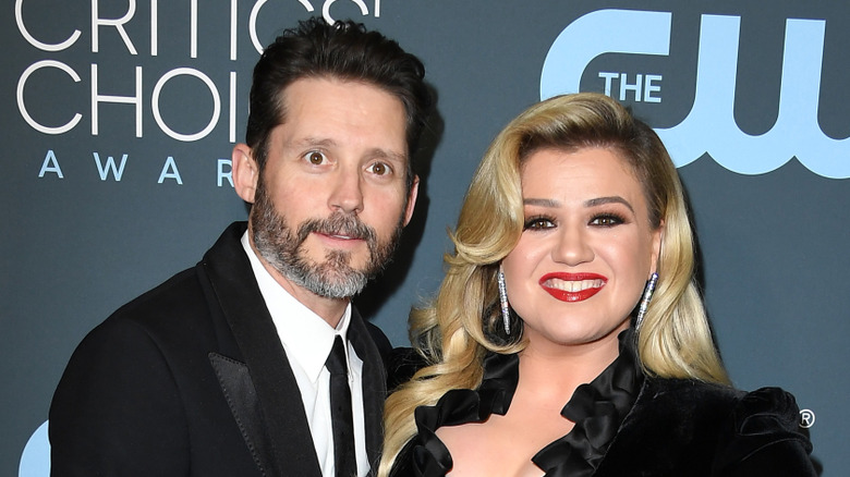 Wide-eyed Brandon Blackstock with arm around smiling Kelly Clarkson