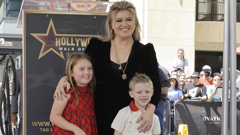 Kelly Clarkson posing with her arms around her children.