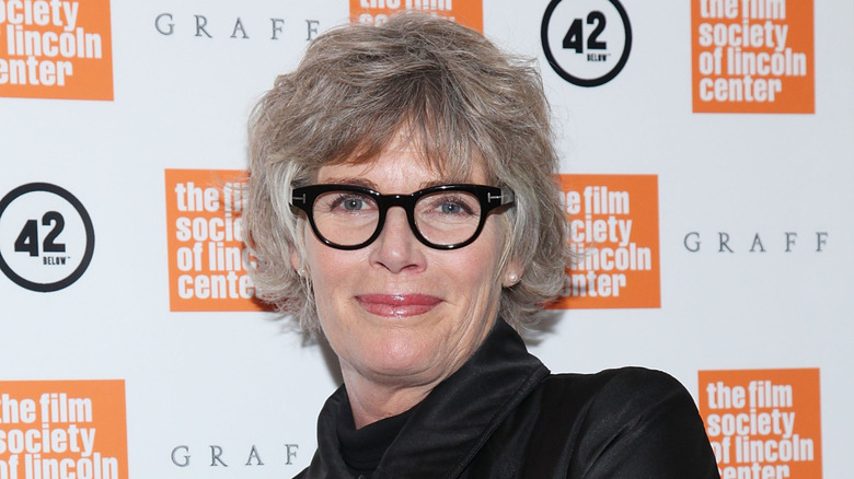 Kelly McGillis smiling while posing at an event in black glasses