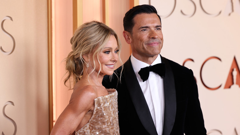 Kelly Ripa and Mark Consuelos pose for cameras on the 2026 Oscars red carpet