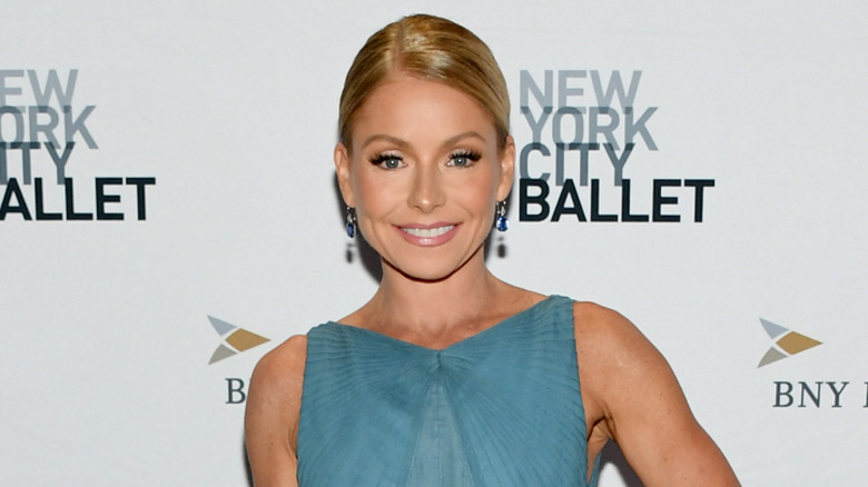 Kelly Ripa smiling while posing at an event in a light blue dress