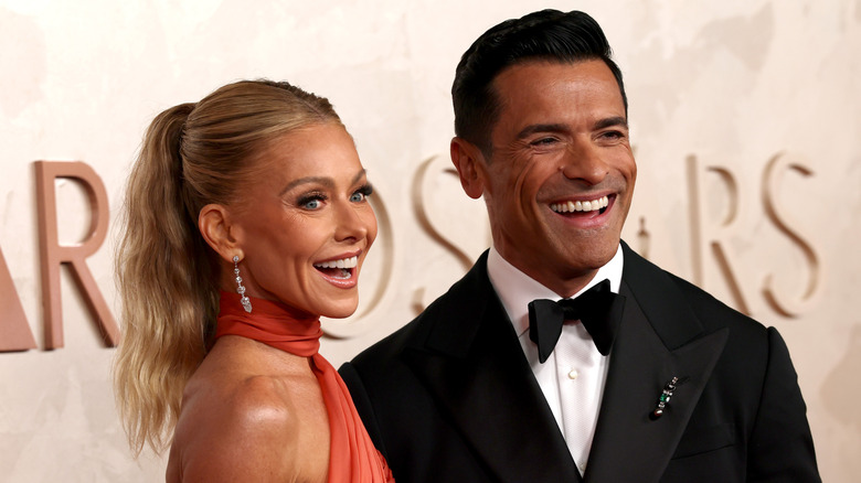 Kelly Ripa and Mark Consuelos smiling while posing at an event together in their finery