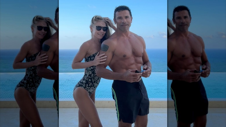 Kelly Ripa places her hand on a shirtless Mark Consuelos' arm as they pose on the beach.