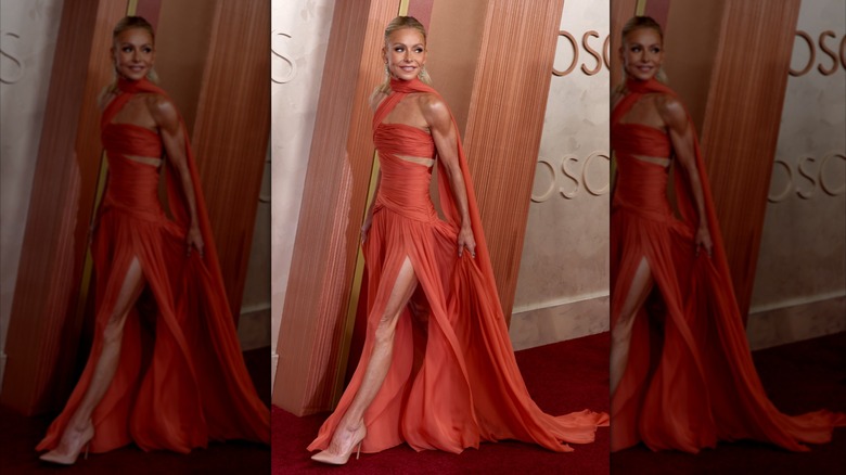 Kelly Ripa walking in a burnt orange wrap dress with a high slit.