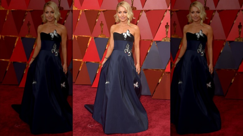 Kelly Ripa posing on the Oscars red carpet in a midnight blue dress with butterfly details