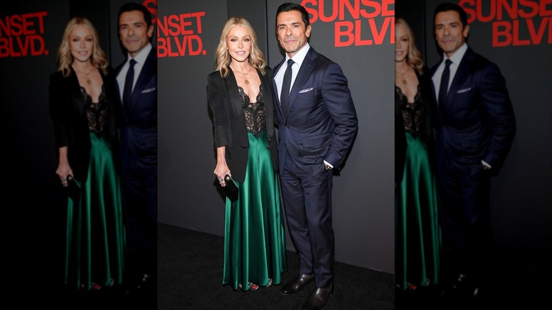Kelly Ripa wearing a dress with a black lace bodice and green silk skirt and posing with Mark Consuelos, who is wearing a dark blue suit