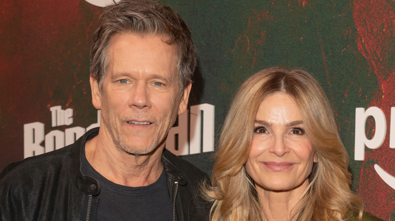 Kevin Bacon and Kyra Sedgwick with a black and red movie poster background