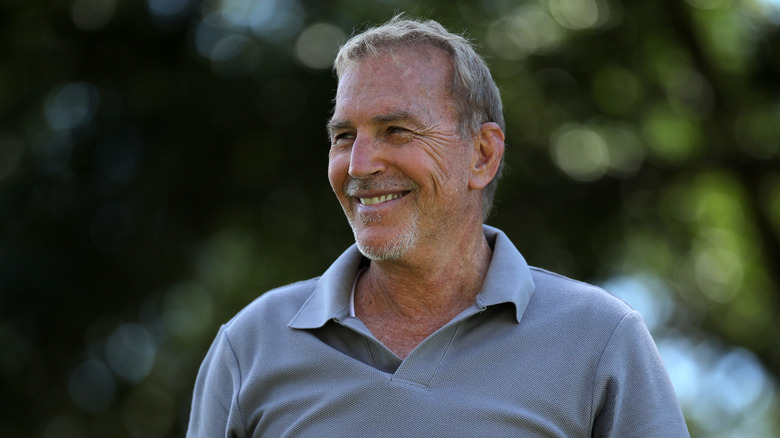 Kevin Costner smiling in a grey golf shirt
