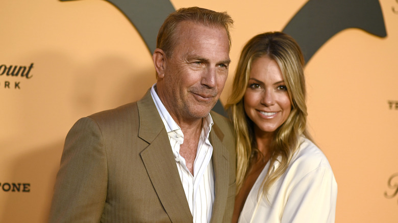 Kevin Costner posing with Christine Baumgartner at an event