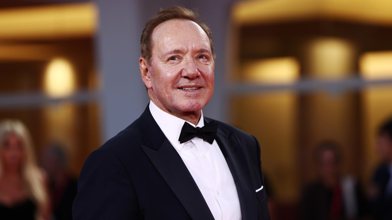 Kevin Spacey smiling for photos in a black tuxedo