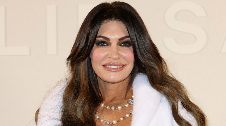 Kimberly Guilfoyle smiling in a white fur with a beaded Chanel necklace