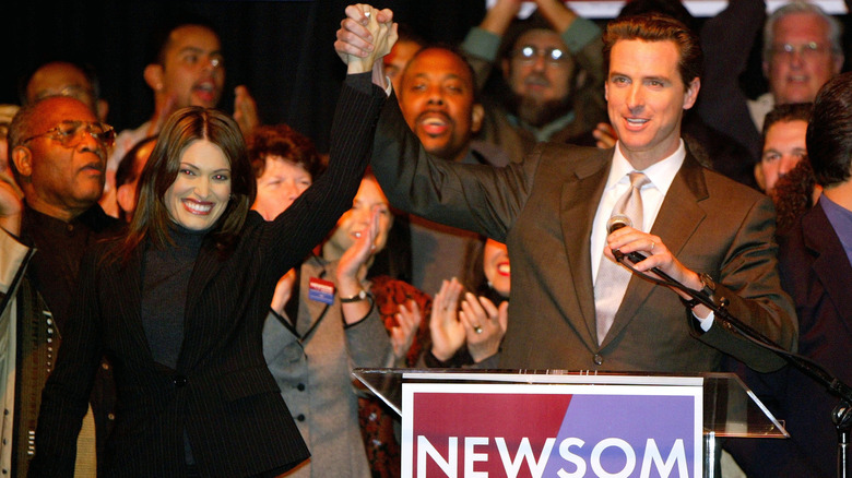 Kimberly Guilfoyle and Gavin Newsom holding hands on stage