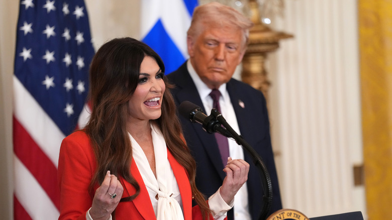 Kimberly Guilfoyle speaking into a microphone while Donald Trump stands behind her