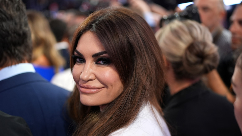 Kimberly Guilfoyle looking over her shoulder in a white top