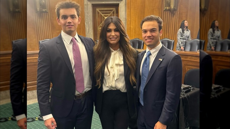 Kimberly Guilfoyle smiling and standing between a young man and her son, Ronan Villency