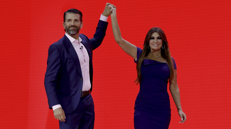 Donald Trump Jr. and Kimberly Guilfoyle holding up hands