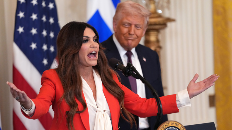 Kimberly Guilfoyle arms open speaking with Trump in background