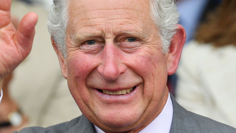 King Charles III smiles and waves