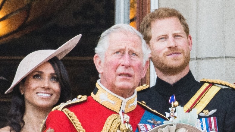 Prince Charles, Prince Harry, and Meghan Markle looking up at parade flyover